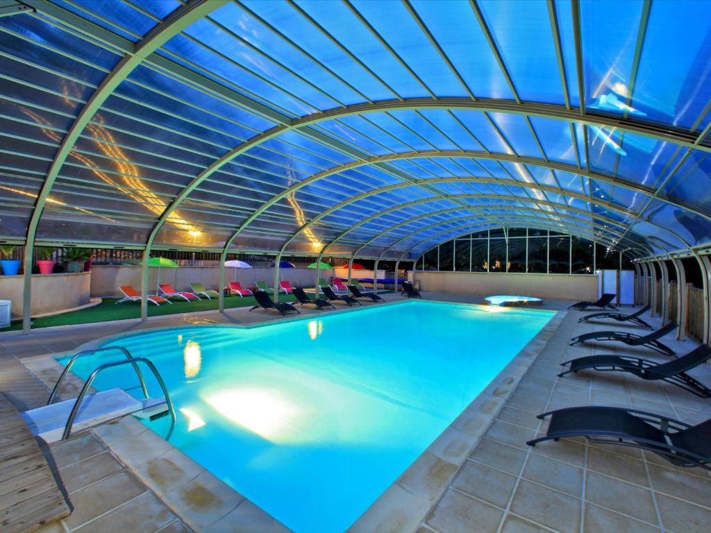 - une piscine avec un plafond voûté et des chaises dans l'établissement Les Chalets du Périgord, à Sarlat-la-Canéda