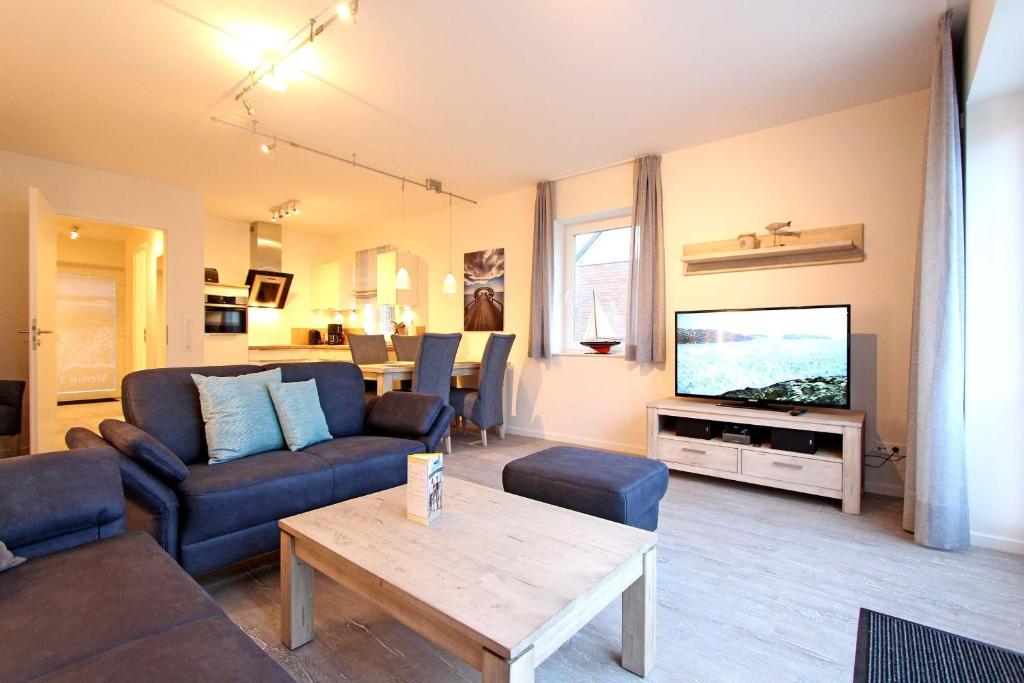 a living room with a couch and a tv at Merlin 3 Waldstr 20 h in Kellenhusen