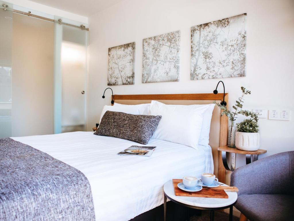 - une chambre avec un lit blanc et une table avec des tasses dans l'établissement Astor Inn, à Wagga Wagga