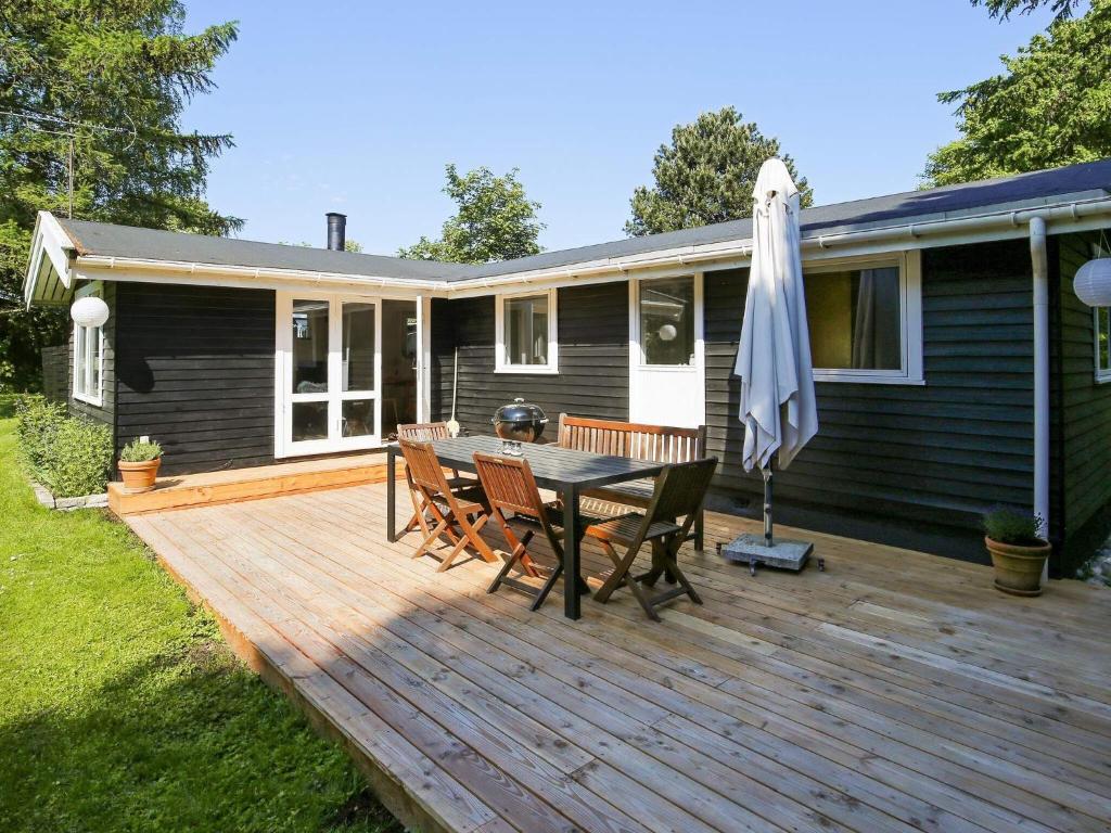 a wooden deck with a table and chairs and an umbrella at 6 person holiday home in Gilleleje in Gilleleje