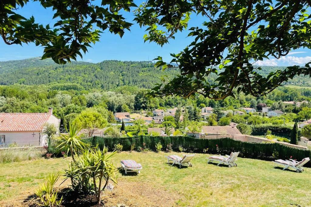 a garden with two chairs and a view of a town at Charmante maison avec jacuzzi in Montazels