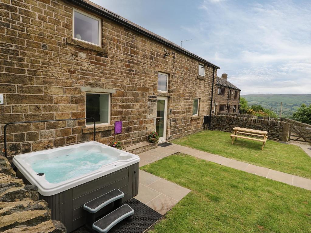 a hot tub in the backyard of a brick house at Upper House Barn Saddleworth in Oldham