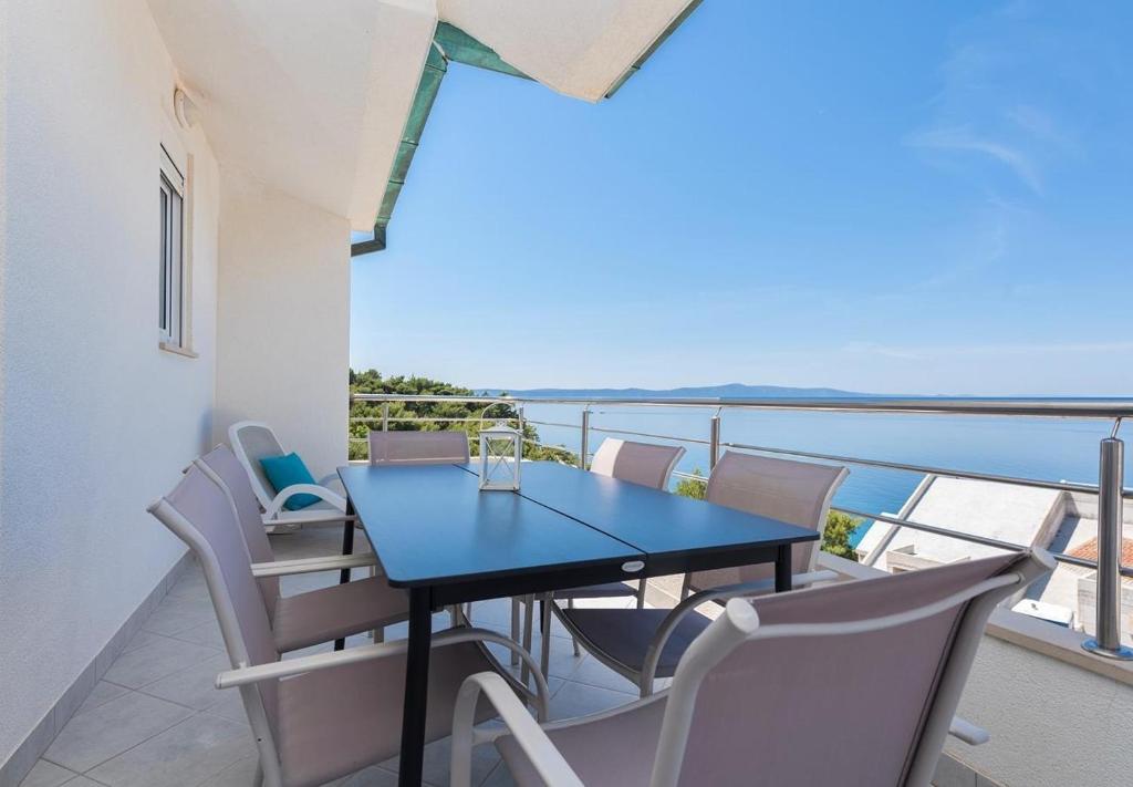 a table and chairs on a balcony with the ocean at Apartments Ivi - 100 m from pebble beach in Drasnice