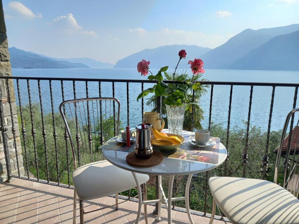 einen Tisch und Stühle auf einem Balkon mit Blick auf das Wasser in der Unterkunft Belvilla by OYO Belvedere 2 in Marone