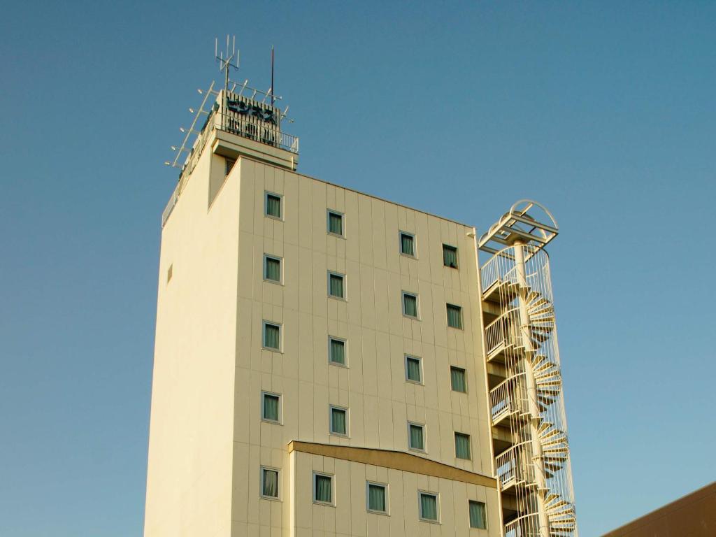 a white building with a tower on top of it at Business Hotel Chateau Est Takamatsu in Takamatsu