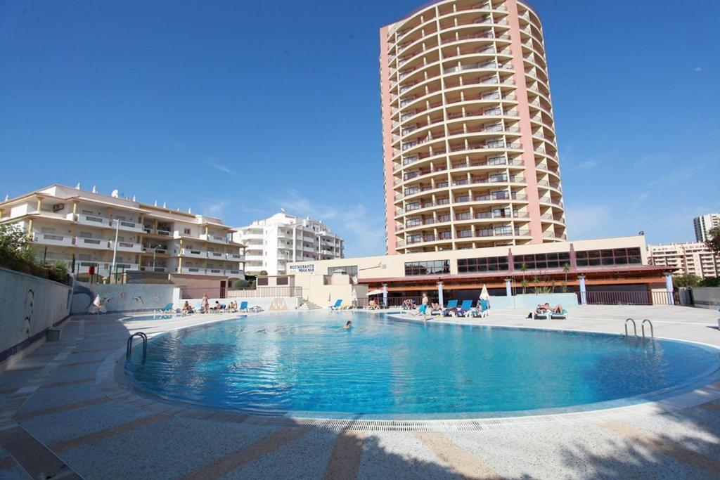 a large swimming pool in front of a tall building at Clube Praia Mar by amcf in Portimão