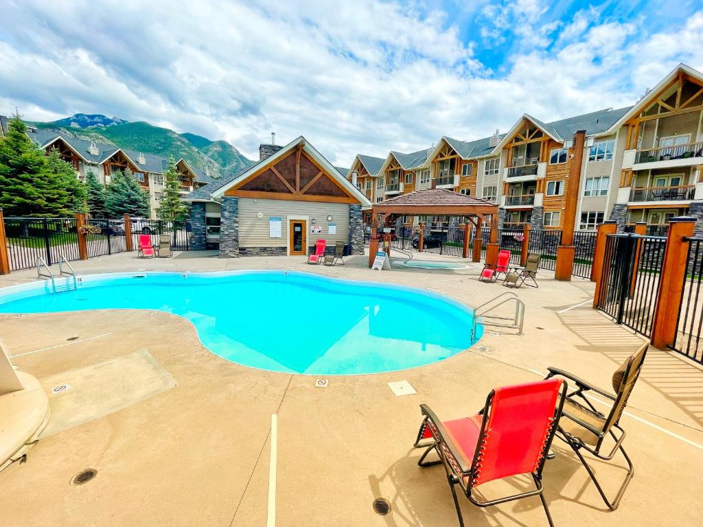 a swimming pool with two chairs and a resort at Sable Ridge Condos by FantasticStay in Radium Hot Springs