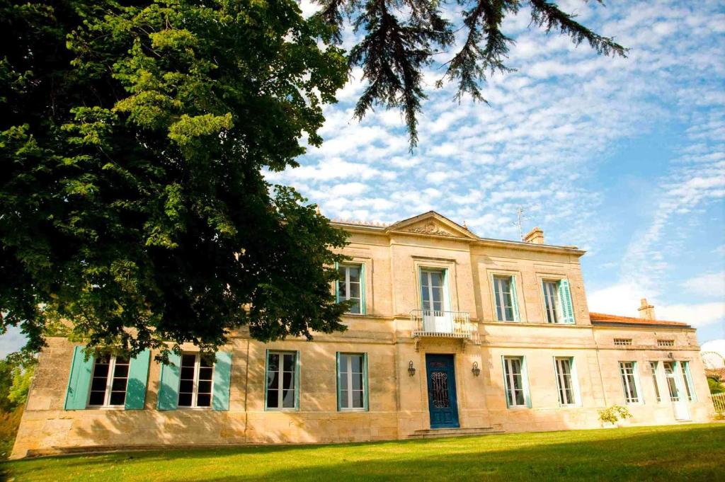 a large stone house with a tree in front of it at Chateau Rousselle in Saint-Ciers-de-Canesse