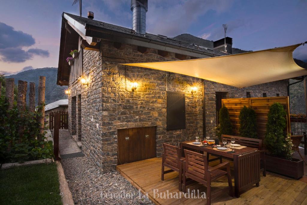 eine Terrasse mit einem Holztisch und ein Gebäude in der Unterkunft Abadía de Montenartró Apartamentos in Montenastró