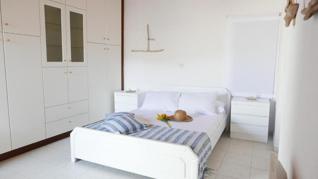 a white bedroom with a bed with a hat on it at Stella's Home in Koronos in Kóronos