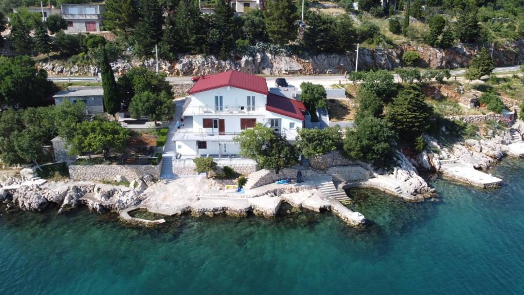 une maison sur une île rocheuse dans l'eau dans l'établissement Apartmani Mila, à Starigrad-Paklenica