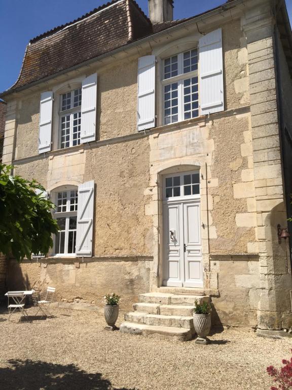 uma antiga casa de pedra com uma porta branca em Le Petit Logis em Rouillac