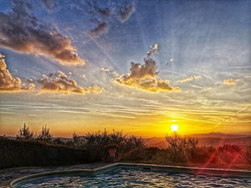 a large pool with a sunset in the background at Il Cerro in Pelago