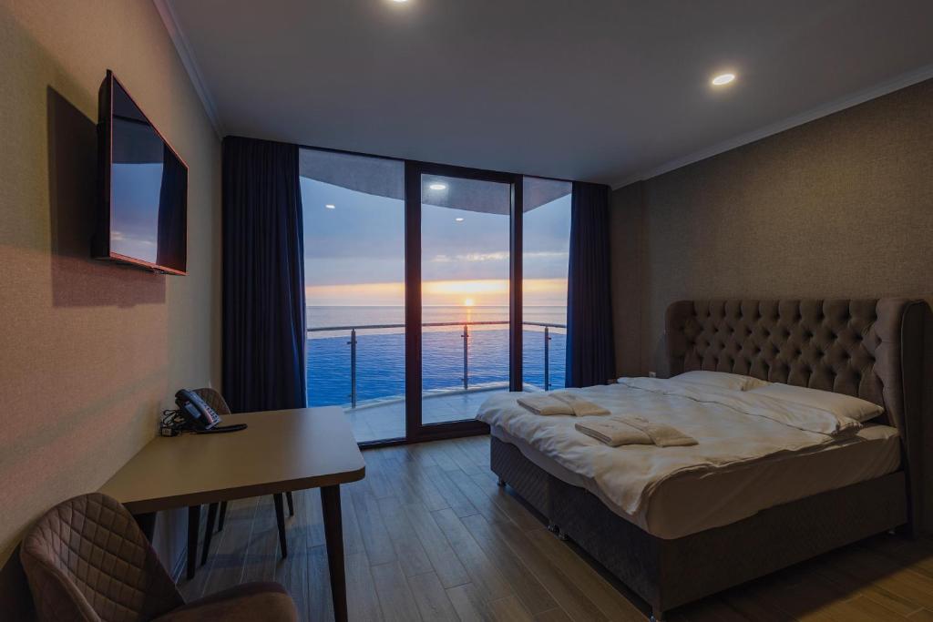 a bedroom with a bed and a view of the ocean at Panorama Kvariati in Kvariati