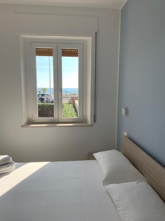 een witte slaapkamer met een bed en een raam bij Appartamento fronte mare con giardino in Porto Recanati