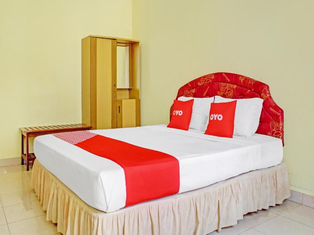 1 dormitorio con 1 cama grande con almohadas rojas y blancas en OYO 90423 Hotel Aman en Palangkaraya