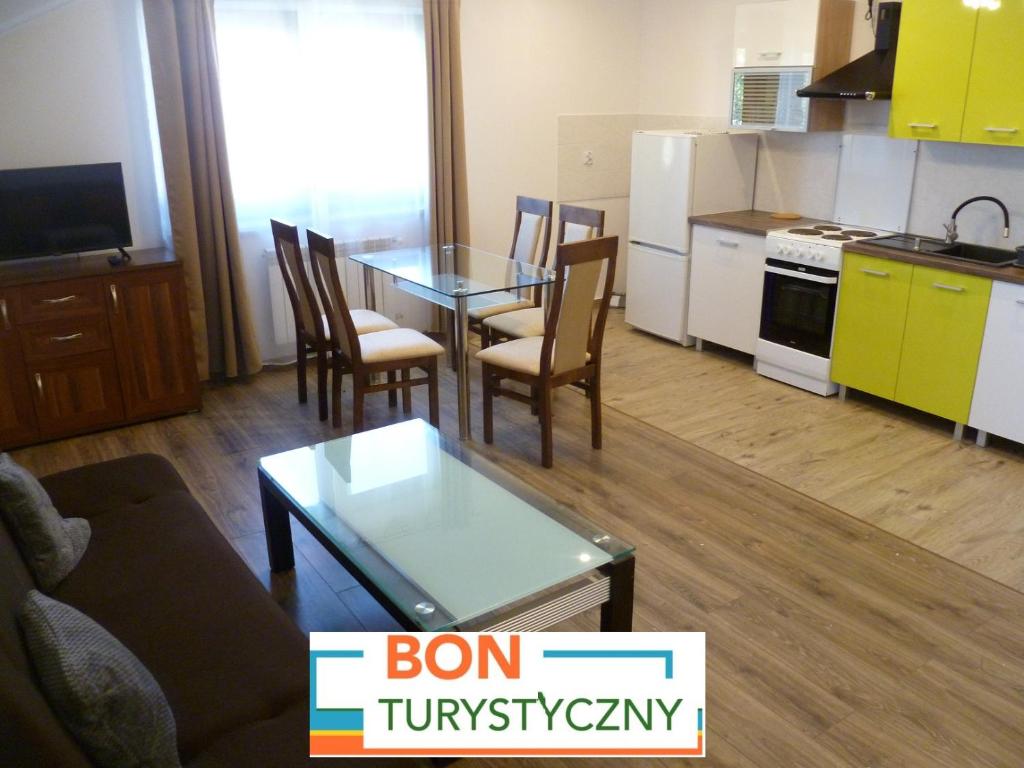 Klimatyczny Domek - Apartamenty & Noclegi في Sławęcin: غرفة معيشة مع طاولة وكراسي ومطبخ