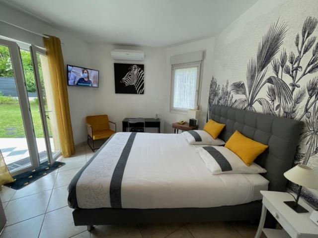 a bedroom with a large bed with yellow and black pillows at STUDIO BEAUREGARD - TERRASSE et JARDIN in Nancy