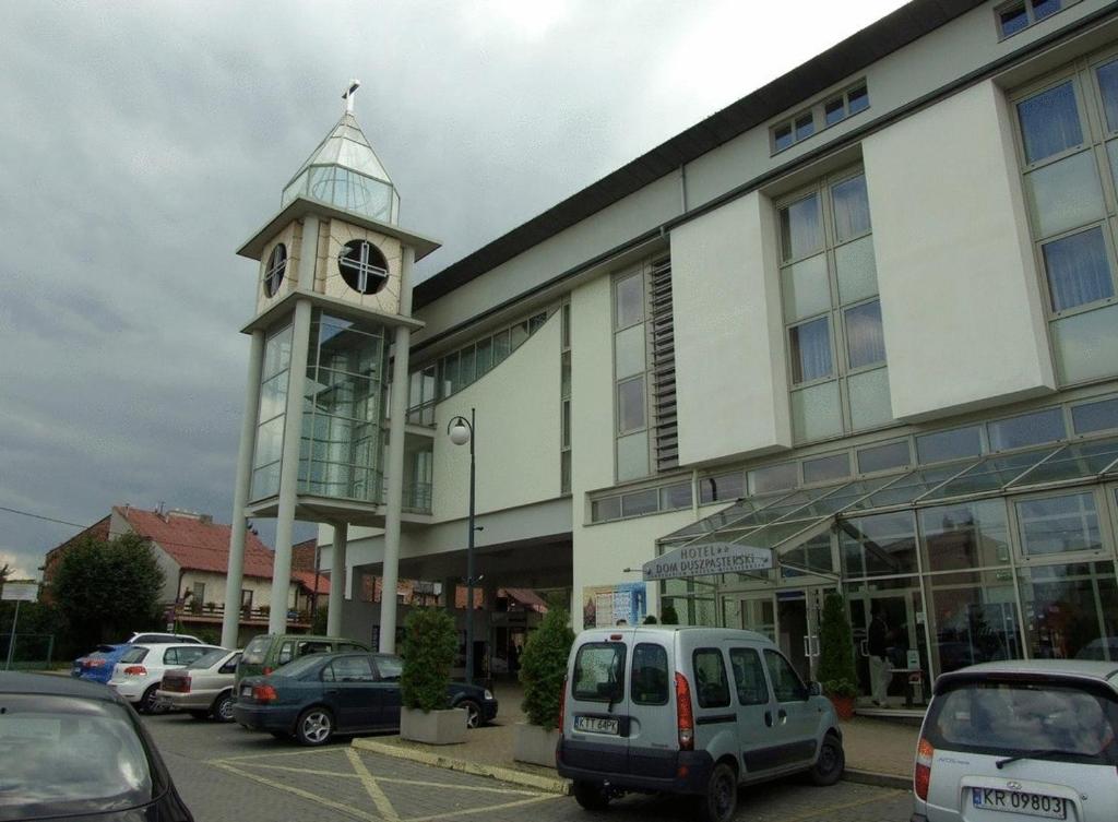 un edificio con una torre de reloj junto a un aparcamiento en Pastoral Lodge at the Sanctuary of the Divine Mercy, en Cracovia