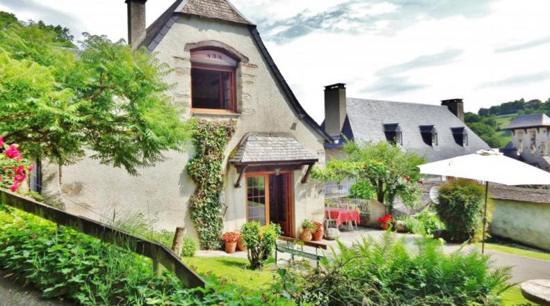 une maison avec un jardin et un parasol dans l'établissement Le gîte d'en haut, à Jarret