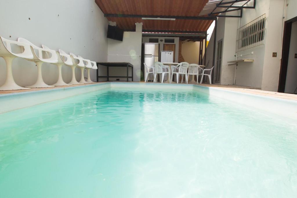 Una gran piscina con sillas y una mesa. en Pousada 45 Hostel, en Belo Horizonte