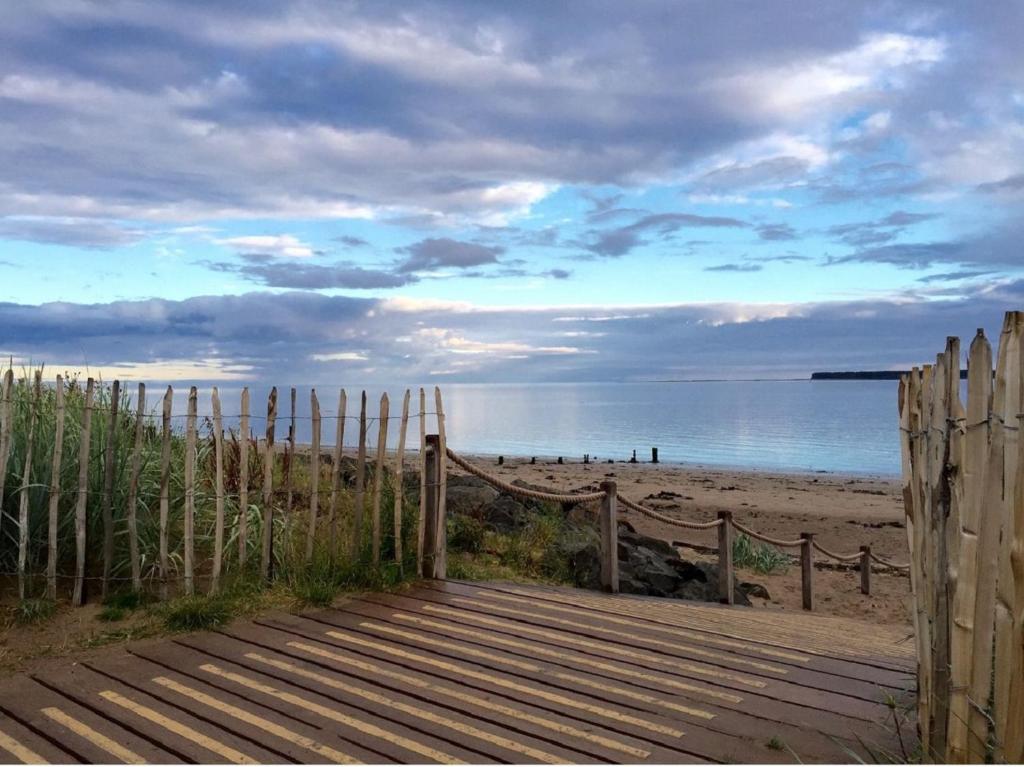 een houten promenade die leidt naar een strand met een hek bij Beach Walk Apartment in Broughty Ferry