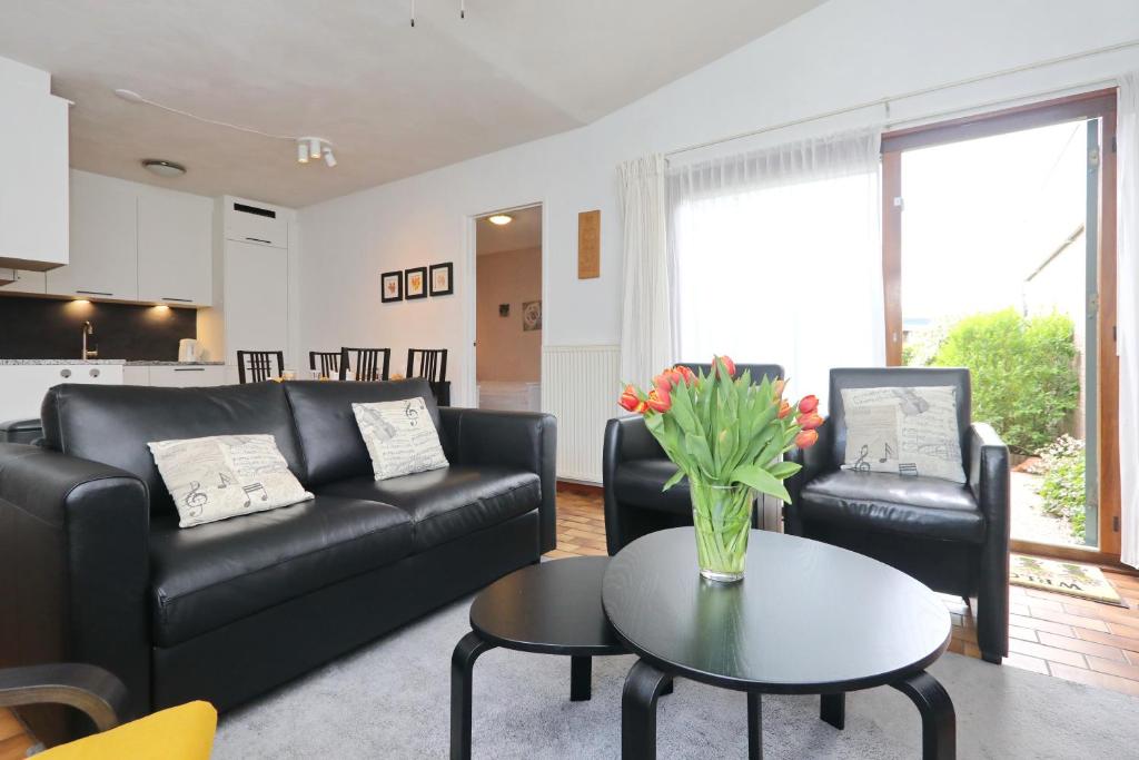 a living room with a black leather couch and a table at Holiday home de Hollandsche Tulp in Noordwijkerhout