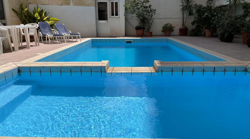 einen großen blauen Pool mit Stühlen im Hof in der Unterkunft Apartment with Private Pool in St Paul's Bay
