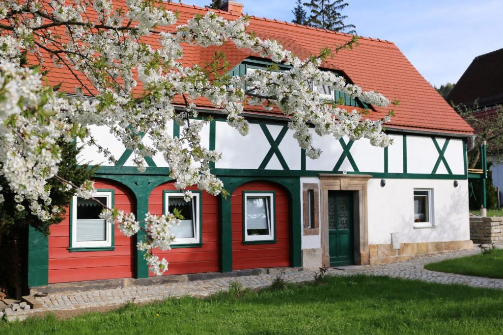 uma casa vermelha e branca com uma árvore florida em Ferienwohnung Zittauer Gebirge em Kurort Jonsdorf