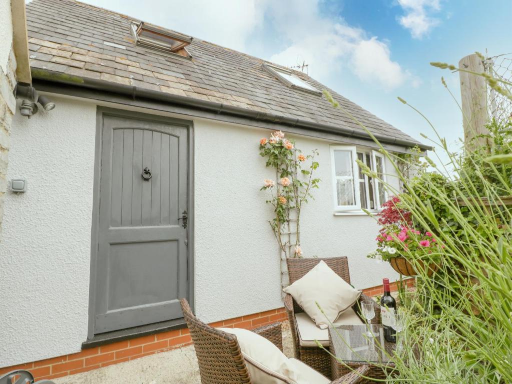 a white house with a grey door and chairs at Dalegarth in Ilminster