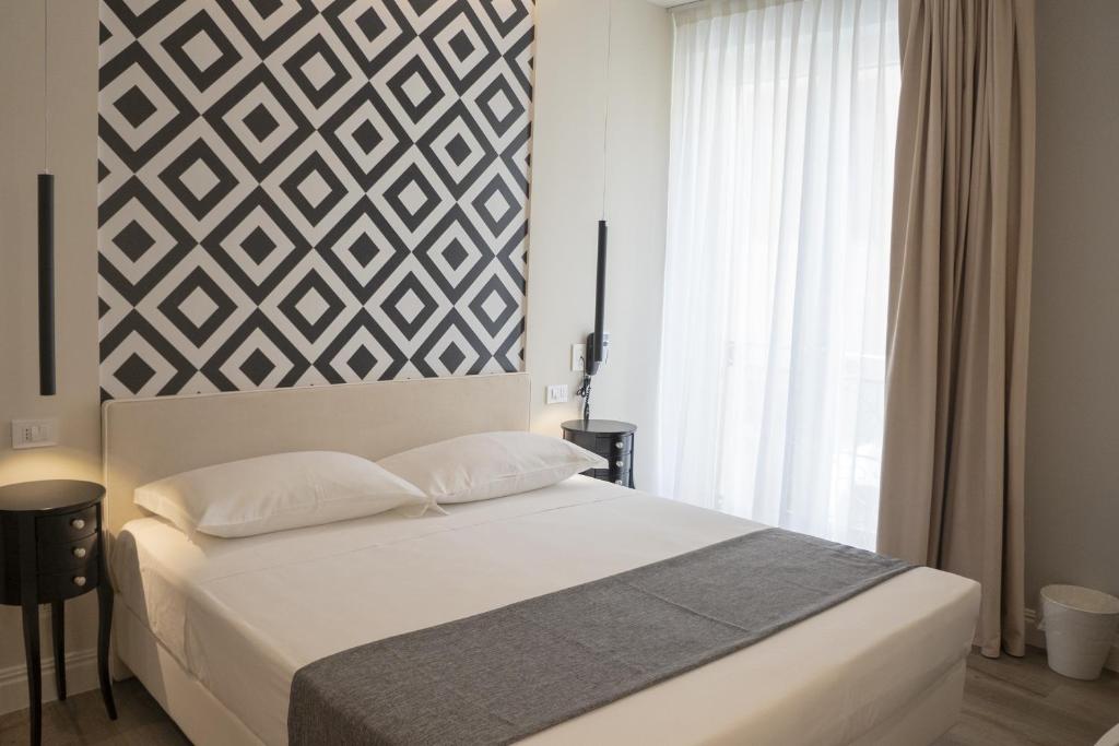 a bedroom with a white bed with a geometric wall at Luxmarì Hotel & Spa in Castellammare del Golfo