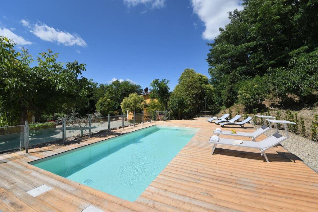 een zwembad met ligstoelen naast een houten terras bij Villa Paradiso in Montevarchi