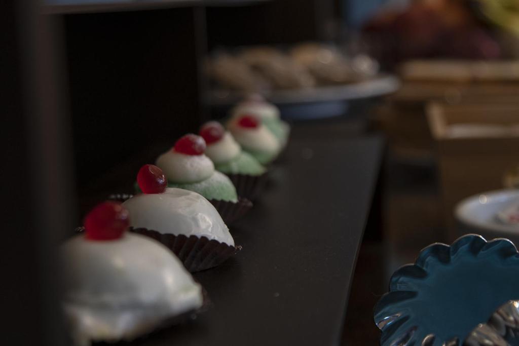 a row of cupcakes with white frosting and cherries at Luxmarì Hotel & Spa in Castellammare del Golfo