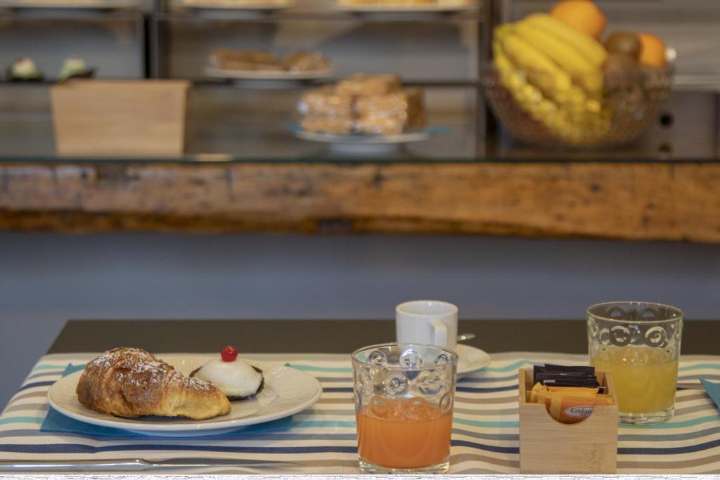 a table with a plate of food and two glasses of orange juice at Luxmarì Hotel & Spa in Castellammare del Golfo
