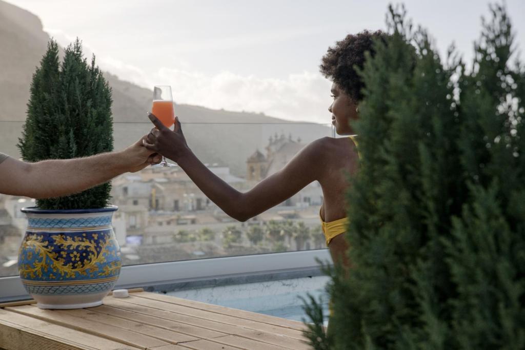 a man and woman holding a glass of wine on a balcony at Luxmarì Hotel & Spa in Castellammare del Golfo