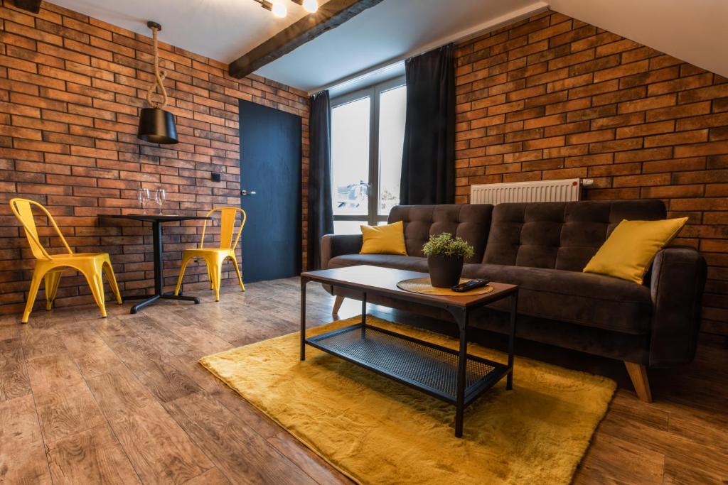 a living room with a couch and a brick wall at Stylowe Apartamenty Plewiska in Plewiska