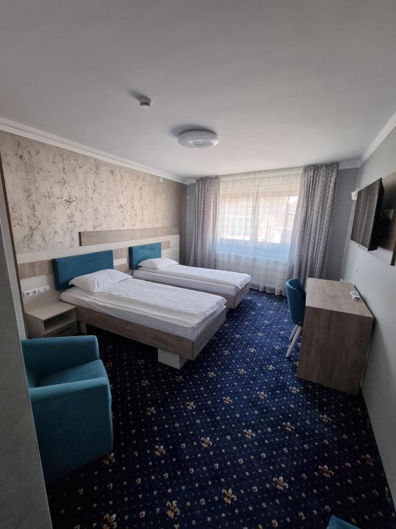 a hotel room with two beds and a table and chairs at Vila El Passo in Târgu-Mureş