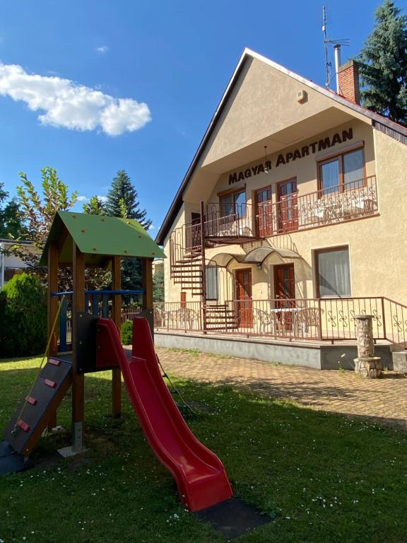 einen Spielplatz mit Rutsche vor einem Gebäude in der Unterkunft Magyar Apartman in Hajdúszoboszló