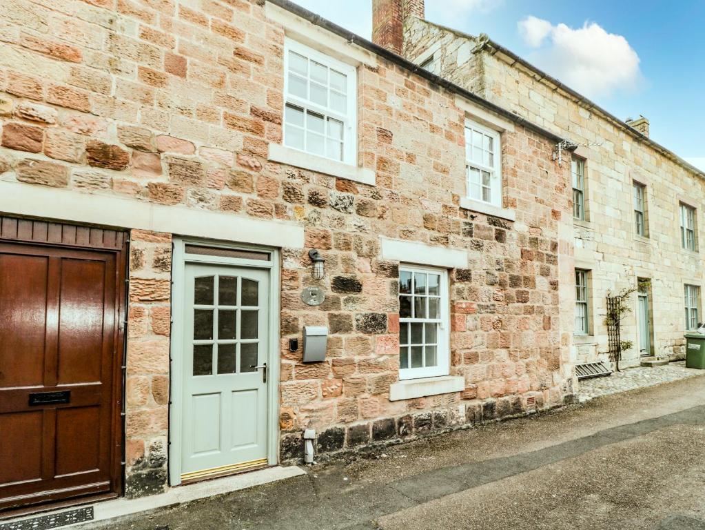 a brick building with a white door and windows at Curlew Cottage, 2 Fenkle Street in Berwick-Upon-Tweed