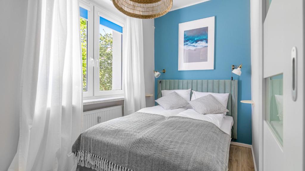 um quarto com paredes azuis e uma cama com almofadas em Comfy Apartments - Błękit Gdyni em Gdynia