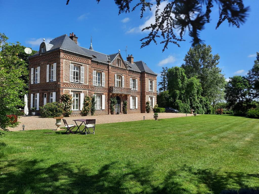 a large red brick building with a grassy yard at Manoir des Tuileries du Buisson in Verneuil d'Avre et d'Iton