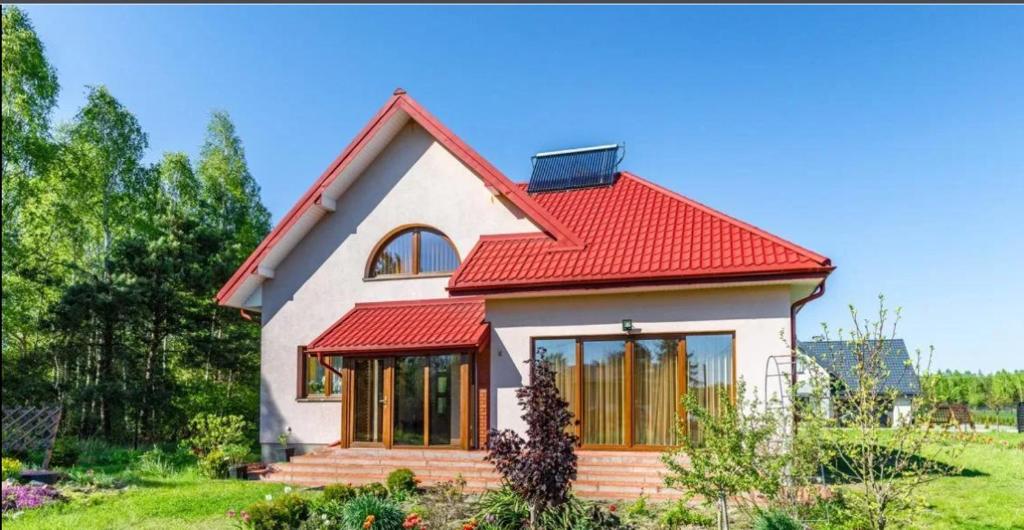 una pequeña casa blanca con techo rojo en Agroturystyka przy lesie en Ludwin
