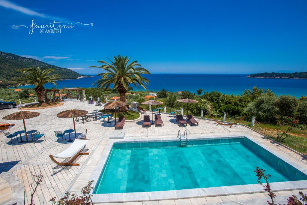 a swimming pool with chairs and umbrellas and the ocean at Kinira Beach Hotel in Koinyra