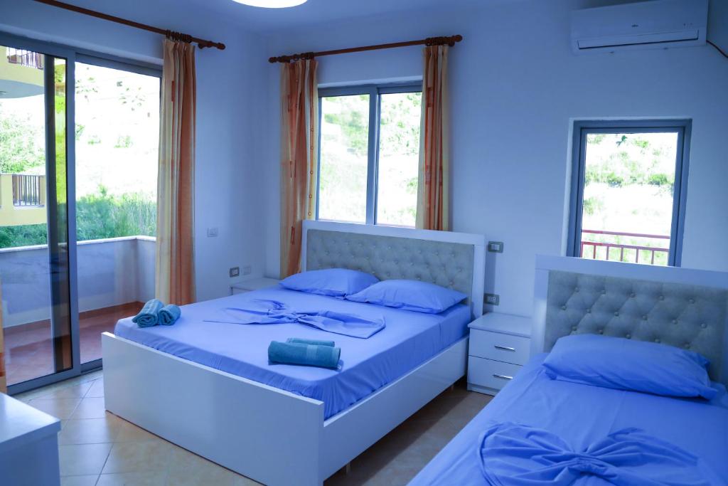 a blue bedroom with two beds and windows at Vila Namiku in Durrës