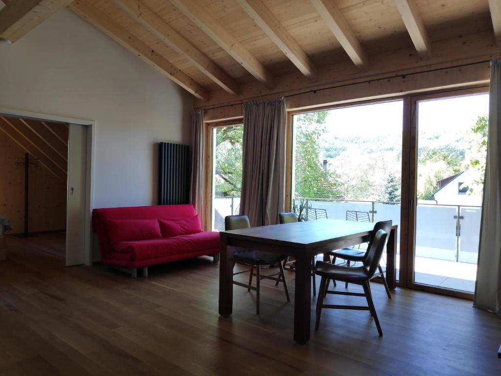 ein Wohnzimmer mit einem Tisch und einem roten Sofa in der Unterkunft Ferienwohnungen und Zimmer in Reutlingen-Gönningen in Reutlingen