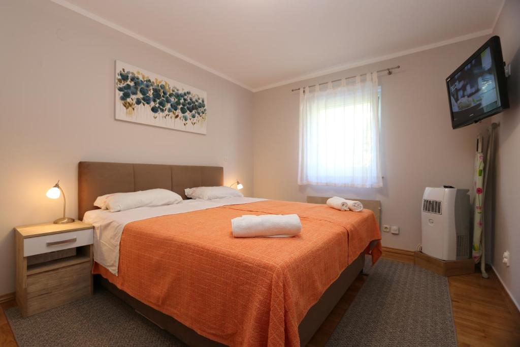 een slaapkamer met een groot bed en een oranje deken bij Apartment Boltar in Šilo