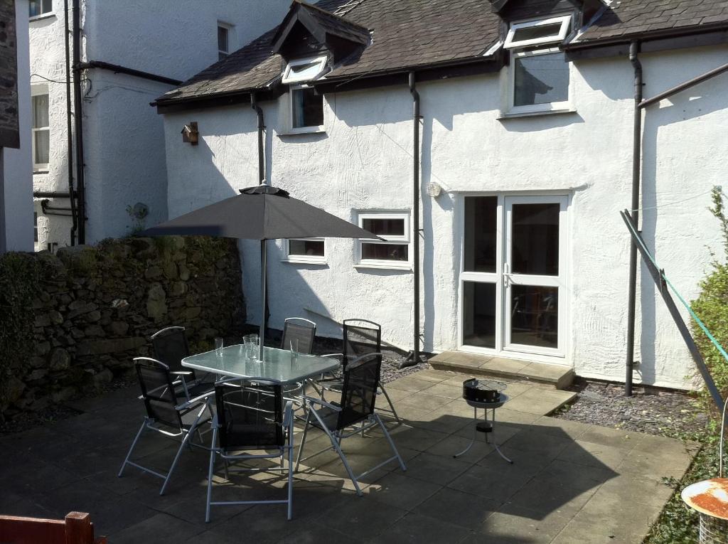 a patio with a table and chairs and an umbrella at Poet's Cottage in Trefriw