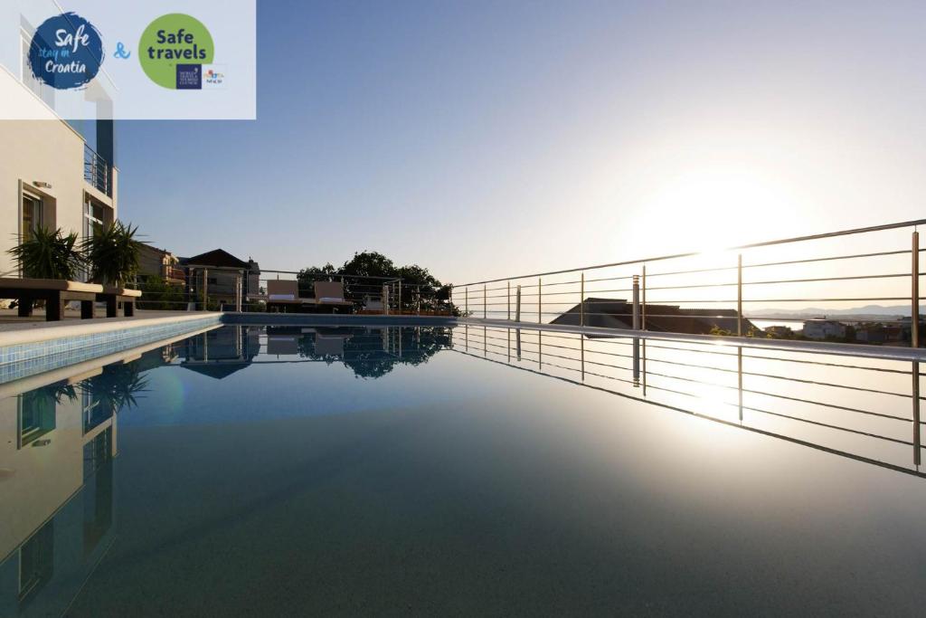 a view of a swimming pool with the sun setting at Villa Mermaid Your Croatian Haven with Luxury Pool and Scenic Views in Podstrana