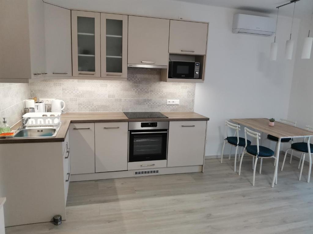 uma cozinha com armários brancos e uma mesa com cadeiras em Éva Apartmanház em Csopak
