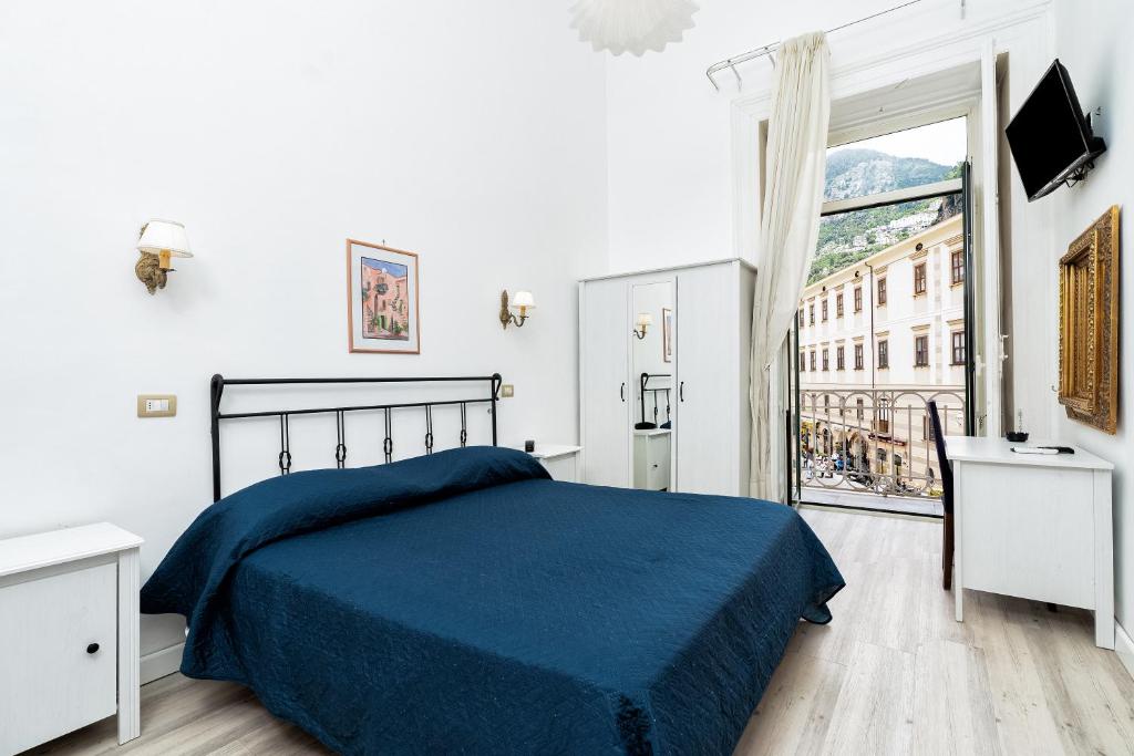 a bedroom with a blue bed and a large window at Hotel Fontana in Amalfi